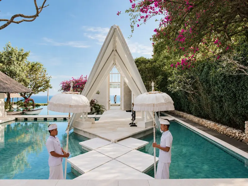 A glass wedding chapel above the ocean in Bali, reached across a turquoise pool