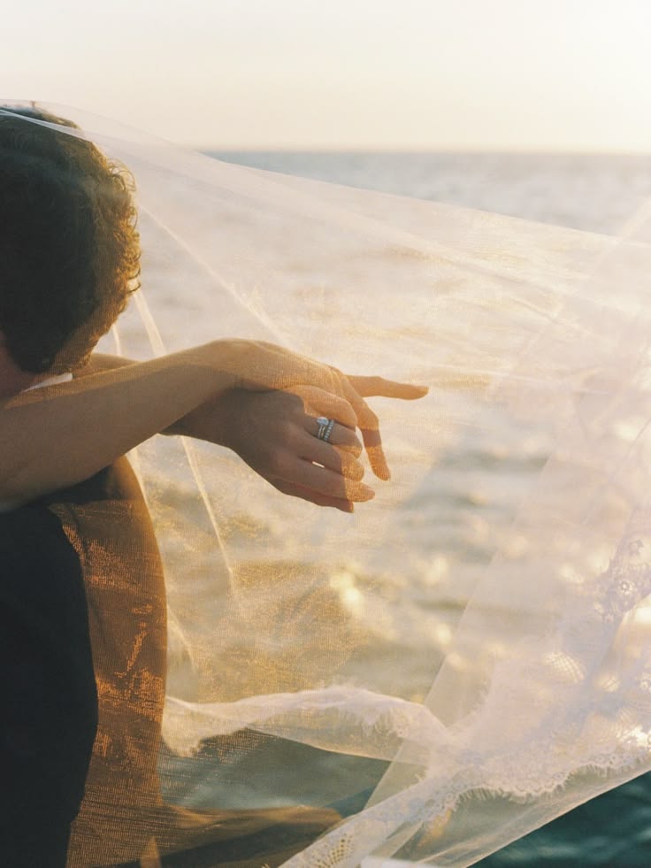 A bride's veil lifting in the sea breeze at golden hour
